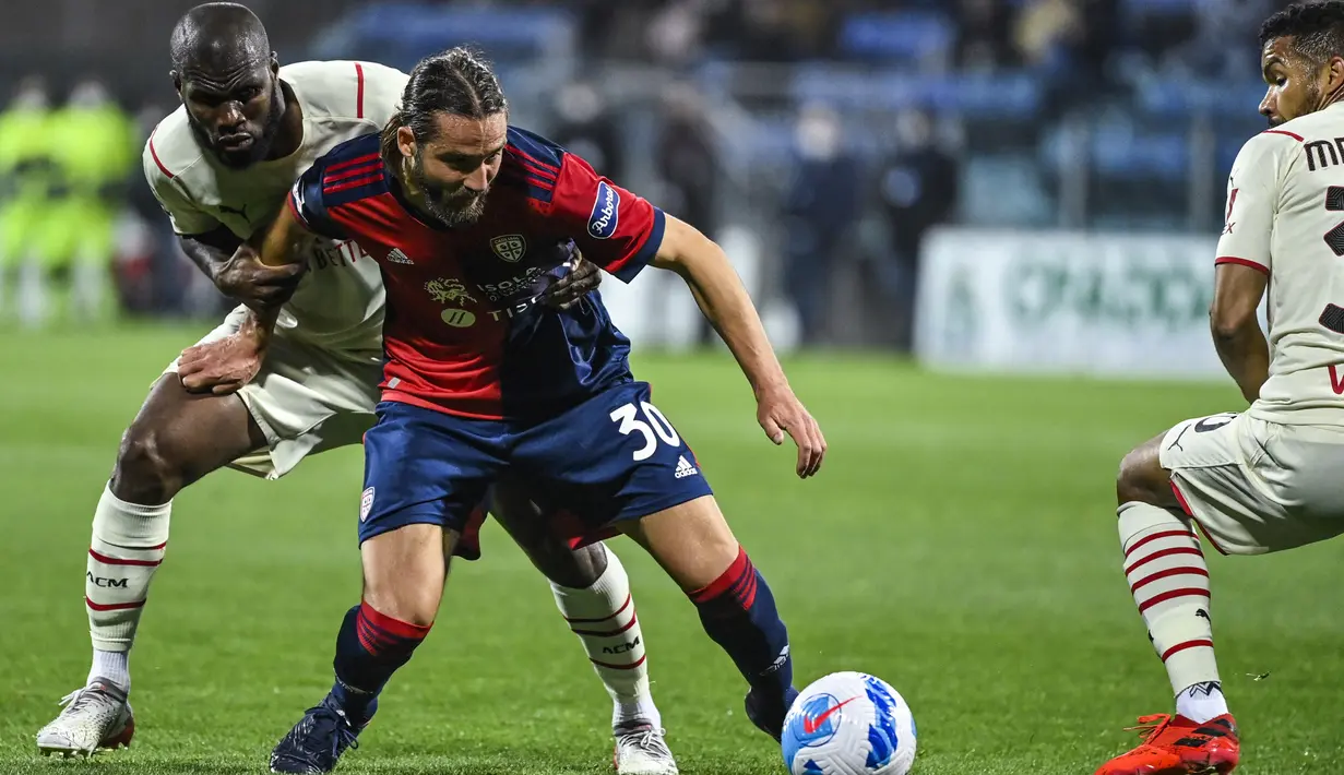 Gelandang AC Milan, Franck Kessie (kiri) menahan penyerang Cagliari, Leonardo Pavoletti selama pertandingan lanjutan Liga Serie A Italia di Sardegna Arena di Cagliari, Italia, Minggu (20/3/2022). Dengan kemenangan ini, AC Milan kokoh di puncak klasemen dengan 66 poin. (AFP/Alberto Pizzoli)