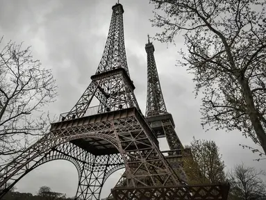 Foto yang diambil pada 1 April 2023 menunjukkan repliqua (kiri) Menara Eiffel, dipasang di dekat yang asli di Paris. (Photo by STEPHANE DE SAKUTIN / AFP)