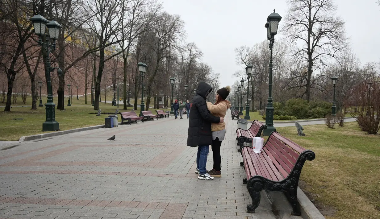 <p>Pasangan berpelukan di Moskow pada 12 April 2022. Jauh dari konflik di Ukraina, musim semi telah tiba di Moskow dengan di permukaan setidaknya kehidupan tampak berjalan seperti biasa. Dengan akan segera berakhirnya musim dingin keras yang terkenal di Rusia, orang-orang Moskow memadati restoran dan teater, berkeliaran di galeri seni dan berjalan-jalan di bawah sinar matahari. (Natalia KOLESNIKOVA / AFP)</p>