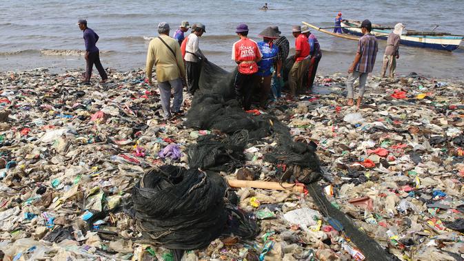 Nelayan beraktivitas di pantai Sukaraja yang tercemar sampah plastik di Bandar Lampung pada 8 September 2019. Selain berserakan dan aroma tak sedap, sampah-sampah di pesisir tersebut juga menyebabkan banyaknya ikan yang mati. (Photo by PERDIANSYAH / AFP)