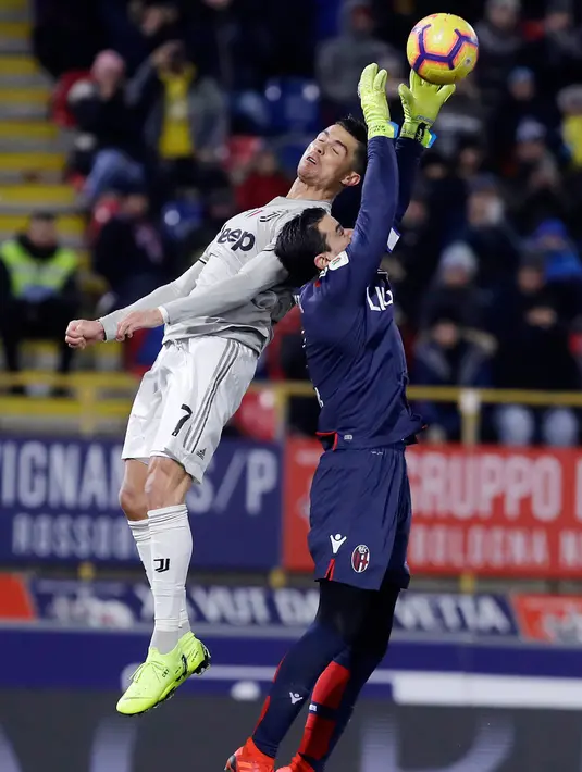 Pemain Juventus Cristiano Ronaldo (kiri) berebut bola udara dengan kiper Bologna Angelo Esmael Da Costa dalam Coppa Italia di Stadion Renato Dall'Ara, Bologna, Italia, Sabtu (12/1). Juventus menang 2-0 atas Bologna. (AP Photo/Luca Bruno)