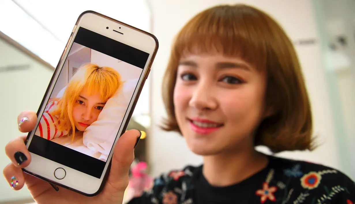 Personel girlband Six Bomb, Kim Da-Young atau Da-In, memperlihatkan foto dirinya sebelum menjalani operasi plastik di sebuah salon kecantikan di Seoul, Korsel, 16 Maret 2017. Da-In menjalani operasi plastik pada bagian atas tubuhnya. (YELIM LEE/AFP)