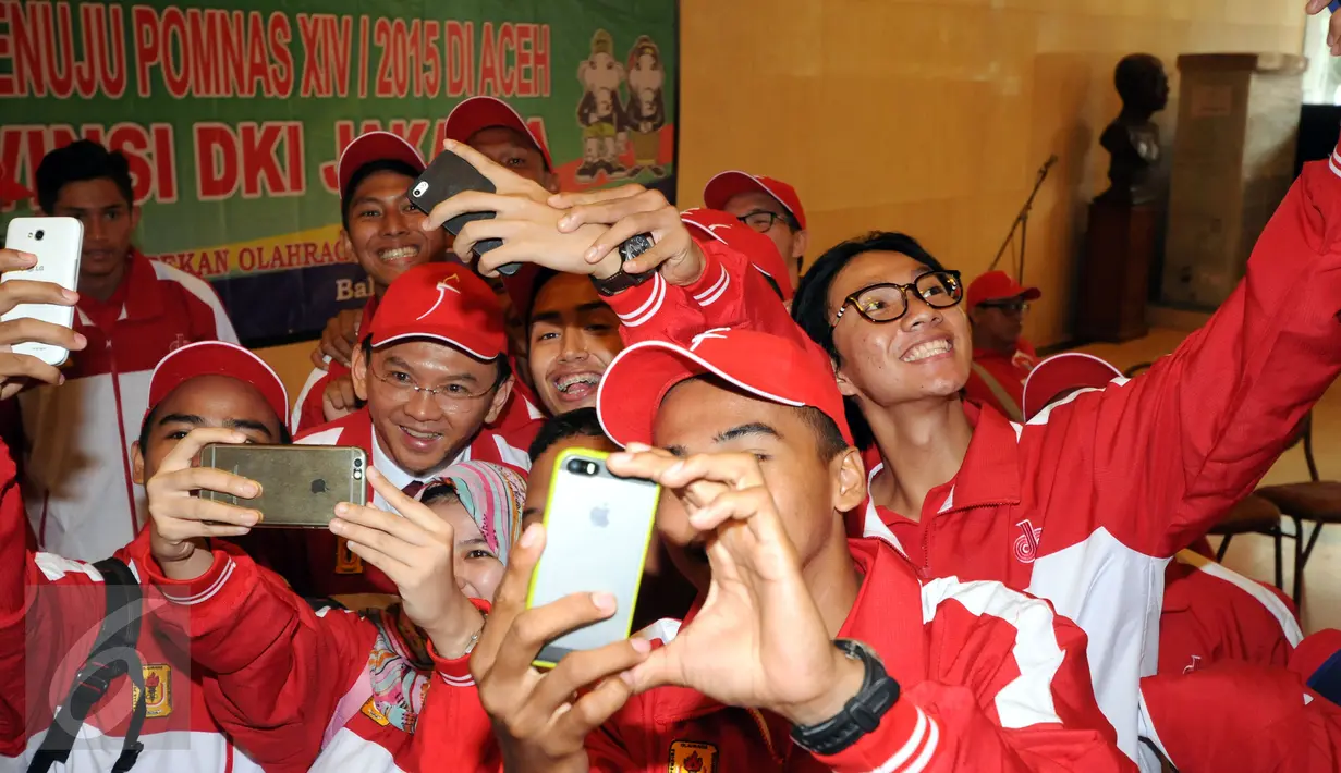 Gubernur DKI Jakarta, Basuki T Purnama (tengah) berselfie bersama kontingen atlit mahasiswa DKI Jakarta Pomnas XIV/Aceh di Balai Agung Jakarta, Selasa (10/11/2015). Jakarta menerjunkan 310 atlit berikut official. (Liputan6.com/Helmi Fithriansyah)  