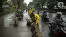 Petugas Sudin Bina Marga merapikan separator busway yang berserakan pascabanjir di Jalan Daan Mogot, Cengkareng, Jakarta, Jumat (3/1/2020). Separator busway tersebut berantakan akibat banjir yang menerjang sejak kemarin. (Liputan6.com/Faizal Fanani)