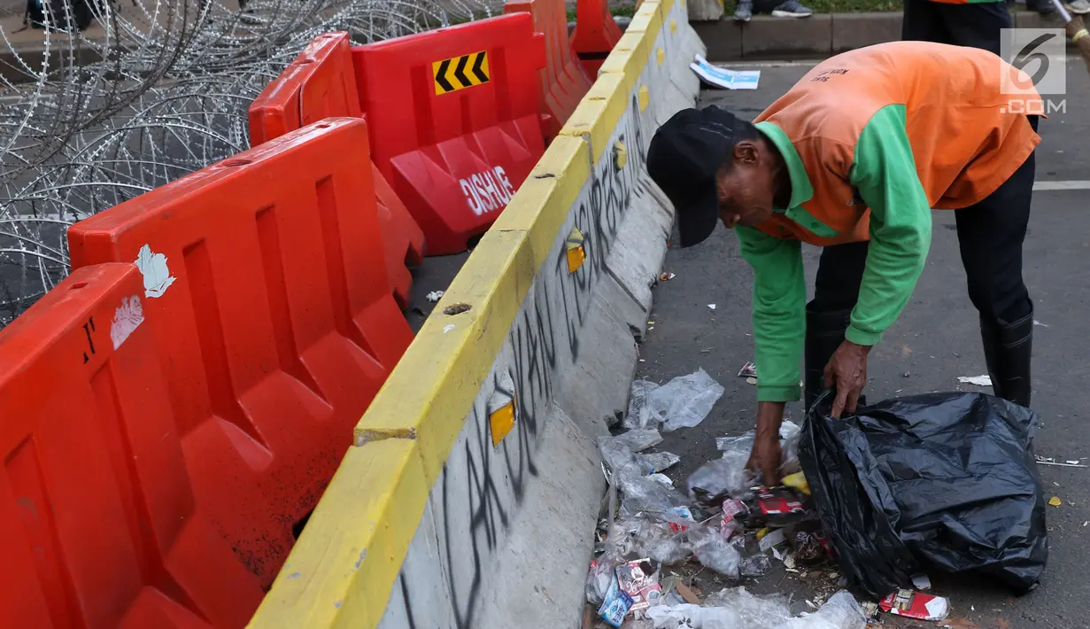 Petugas PPSU membersihkan sampah sisa perayaan Hari Buruh Internasional di kawasan Silang Barat Daya Monas, Jakarta, Rabu (1/5). Sampah yang berserakan di kawasan tersebut membuat Petugas PPSU bekerja ekstra keras untuk membersihkan kawasan tersebut. (Liputan6.com/Helmi Fithriansyah)