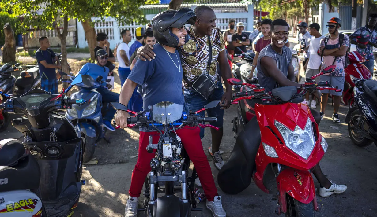 Orang-orang berkumpul di skuter listrik mereka untuk menghabiskan sore hari memamerkan aksi dan balapan di Havana, Kuba, pada 15 Juli 2022. Kuba telah dibanjiri dalam beberapa tahun terakhir dengan "motorinas", begitu skuter listrik ini disebut di pulau itu, sebuah mode bagi banyak orang, tetapi juga solusi untuk masalah transportasi dan kekurangan bahan bakar yang melanda negara Karibia itu. (AP Photo/Ramon Espinosa)