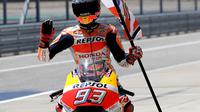 Pembalap Repsol Honda, Marc Marquez membawa bendera saat berselebrasi usai memenangi balapan MotoGP Amerika di Circuit of the Americas (COTA), Austin, Minggu (22/4). Hasil ini menjadi kemenangan keenam Marquez secara beruntun di Amerika. (AP/Eric Gay)