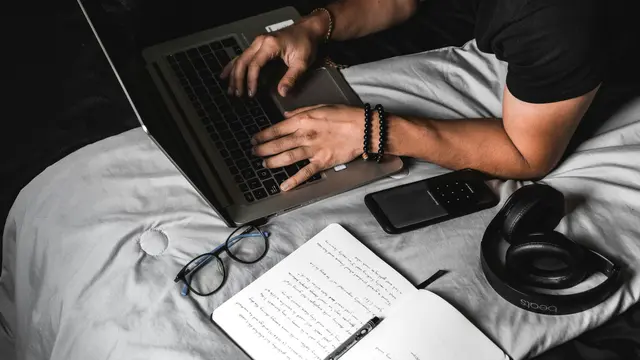 Laptop di Atas Kasur/Photo by Fernando Hernandez on Unsplash