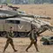 Tentara Israel berjalan melewati tank di dekat perbatasan Gaza-Israel, Jumat (19/10). PM Benjamin Netanyahu berjanji bakal mengambil tindakan tegas apabila warga Palestina masih terus melancarkan serangan ke wilayah Israel. (AP Photo/Ariel Schalit)