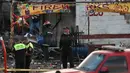 Petugas pemadam dan tim pertolongan berdiri dekat bangunan rumah yang hancur dalam ledakan pasar kembang api terbesar di luar Ibu Kota Meksiko, Selasa (20/12). Sedikitnya 27 orang tewas dan lebih dari 70 lainnya terluka. (REUTERS/Edgard Garrido)