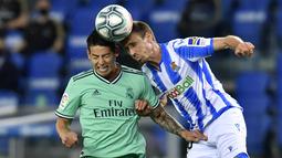 Pemain Real Madrid, James Rodriguez, duel udara dengan pemain Real Sociedad, Nacho Monreal, pada laga La Liga di Reale Seguros Stadium, Minggu (21/6/2020). Real Madrid menang 2-1 atas Real Sociedad. (AP Photo/Alvaro Barrientos)