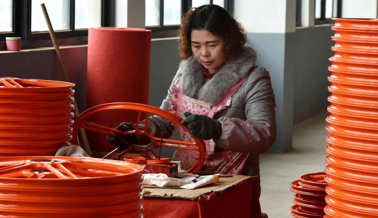 Seorang pekerja wanita mengecek kondisi pelek di pabrik pembuatan pelek sepeda motor di Jinhua, Provinsi Zhejiang, China (14/1). (AFP Photo/China Out)