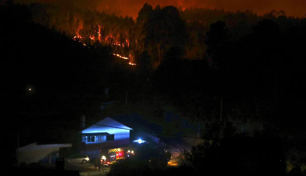 Mobil pemadam kebakaran diparkir dekat rumah-rumah untuk melindungi mereka dari kebakaran hutan yang mengamuk di Desa Serra do Branco, dekat Leiria, Portugal, 12 Juli 2022. Ratusan petugas pemadam kebakaran di Portugal terus memadamkan api di pusat negara yang memaksa evakuasi puluhan orang dari rumah mereka sebagian besar di desa-desa sekitar Santarem, Leiria, dan Pombal. (AP Photo/Joao Henriques)
