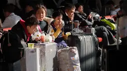 Otoritas transportasi China memprediksi, ada sekitar 9,5 miliar perjalanan penumpang akan dilakukan selama periode arus mudik yang akan berakhir pada 13 Maret 2026. Tampak dalam foto, para penumpang duduk di samping barang bawaan mereka sambil menunggu di stasiun kereta api dalam perjalanan pulang selama liburan Tahun Baru Imlek di Beijing, China, Selasa 10 Februari 2026. (AP Photo/Vincent Thian)