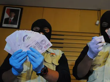 Dua orang penyidik KPK memperlihatkan uang suap yang diduga untuk anggota DPR Fraksi PDIP Adriansyah, Jakarta, Jumat (10/4/2015). KPK berhasil menangkap tangan pelaku saat bertaransaksi di Bali.(Liputan6.com/Herman Zakharia) 