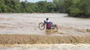 Seorang pria yang membawa sepedanya melintasi Sungai Muuoni yang banjir, dimana 8 orang dikabarkan tenggelam dalam semalam saat menyeberangi sungai di kawasan Mukaa, kabupaten Makueni, wilayah Timur Kenya, Jumat, 24 November 2023. (AP Photo)