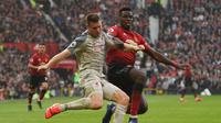 Paul Pogba mencoba menghentikan James Milner pada laga lanjutan Premier League yang berlangsung di stadion Old Trafford, Manchester, Minggu (24/2). Man United bermain imbang 0-0 kontra Liverpool. (AFP/Oli Scarff)