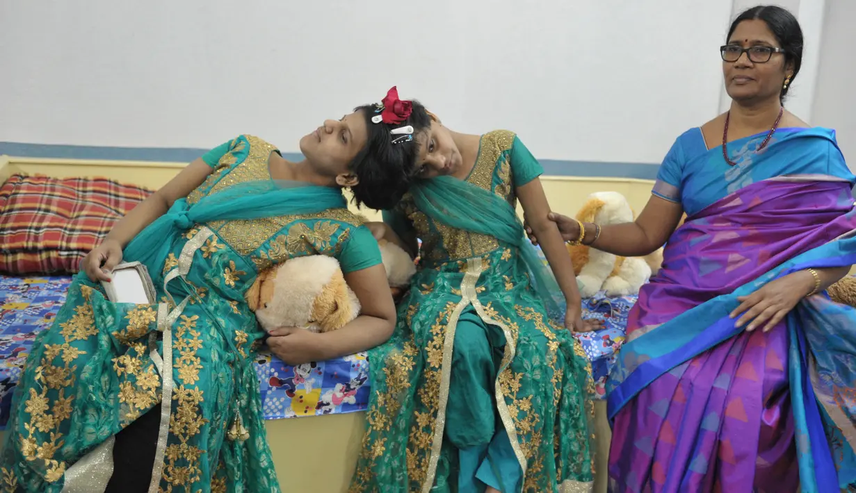 Anak kembar siam, Veena (kanan) dan Vani yang berusia 14 tahun didampingi Direktur Joint Regional untuk Pembangunan Perempuan dan Kesejahteraan Anak, D. Lalitha Kumari di Rumah Anak di Hyderabad, India (2/1). (AFP/Noah Seelam)