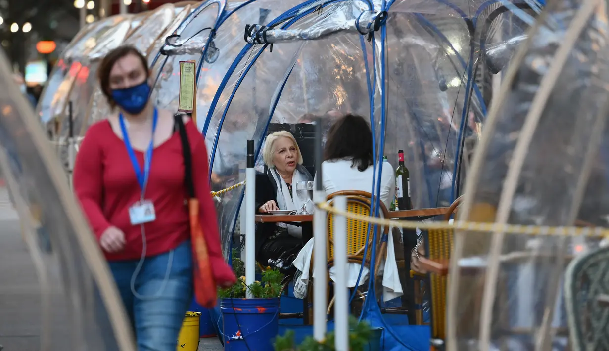 Orang-orang menikmati makanan di dalam tenda plastik untuk menjaga jarak di sebuah restoran di Manhattan, New York City, Kamis (15/10/2020). Konsep gelembung luar angkasa ini menawarkan sensasi tersendiri sekaligus berjaga-jaga dari resiko penularan COVID-19 bagi para pelanggan. (Angela Weiss/AFP)