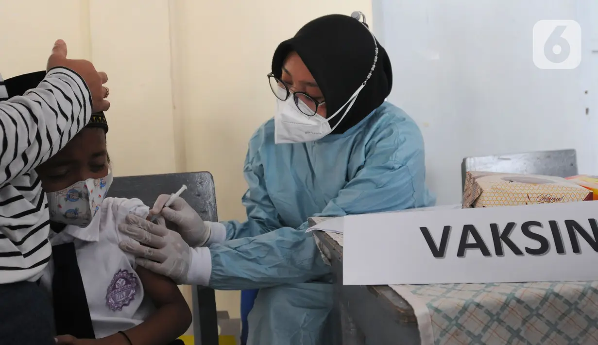 Petugas menyuntikkan vaksin covid-19 dosis kedua kepada murid kelas II di SDI Al Hidayah, Depok, Selasa (25/1/2022). Mengantisipasi meningkatnya kasus Omicron, pemerintah mempercepat vaksinasi untuk lansia dan anak-anak, baik itu vaksin dosis pertama, kedua, maupun booster. (merdeka.com/Arie Basuki)