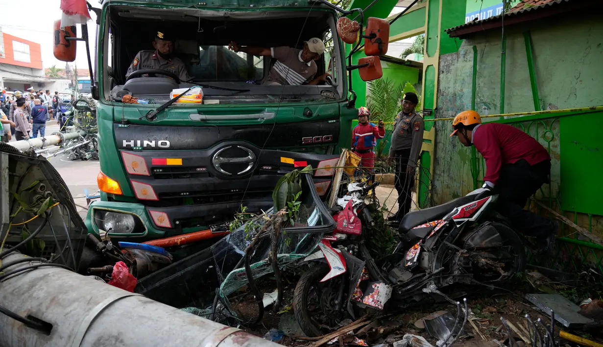 Polisi membersihkan puing-puing pascakecelakaan lalu lintas di Bekasi, Indonesia, Rabu (31/8/2022). Korban meninggal adalah siswa SD dan pedagang. (AP Photo/Achmad Ibrahim)