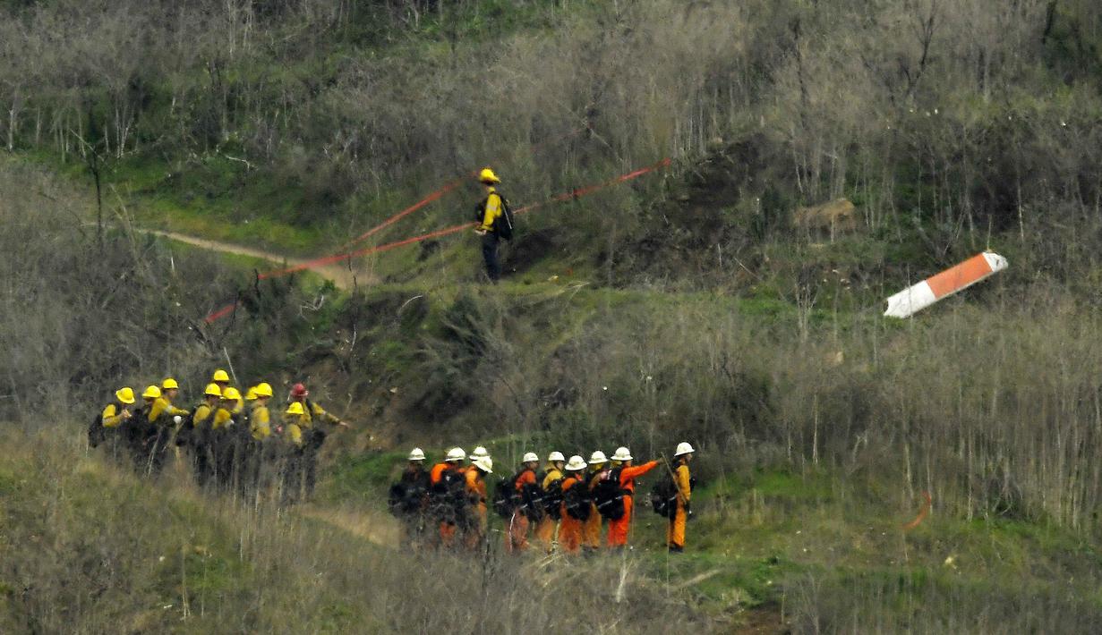 Sejumlah petugas berusaha mengevakuasi korban jatuhnya helikopter di Calabasas, California, Minggu (26/1/2020). Legenda NBA, Kobe Bryant, menjadi salah satu korban tewas pada kecelekaan helikopter berjenis Sikorsky S-76B itu. (AP/Mark J. Terrill)