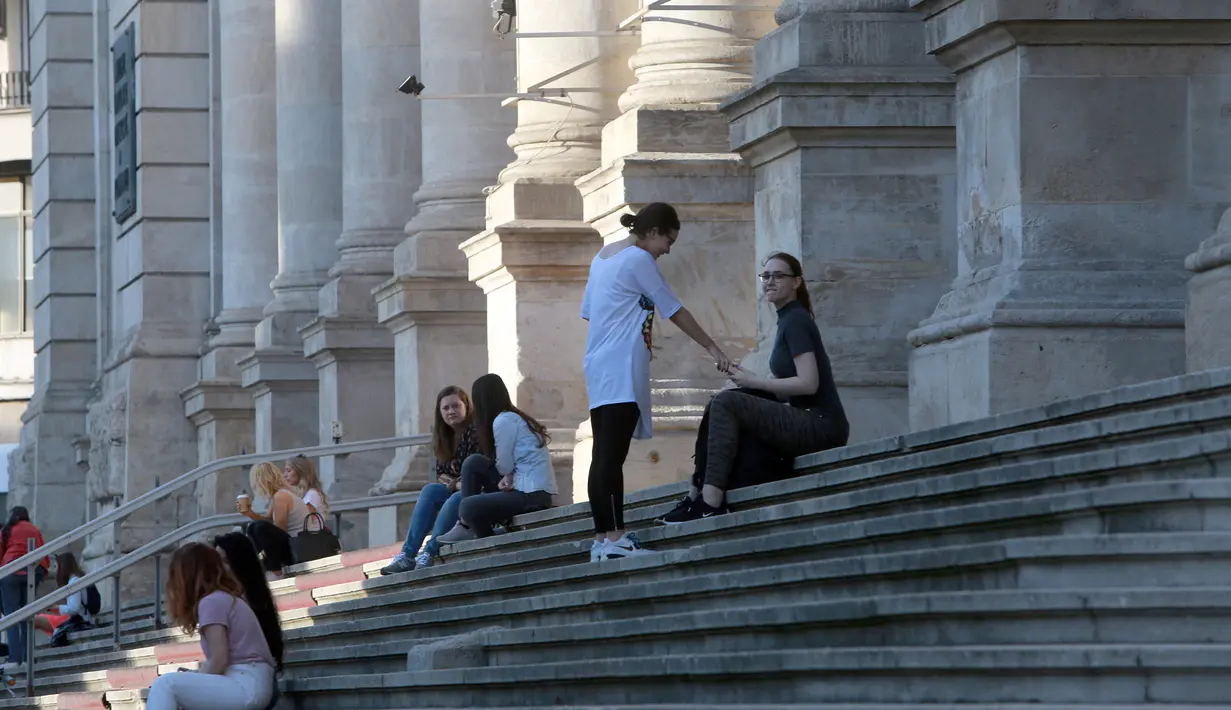 Warga tampak duduk di tangga halaman depan Museum Sejarah Nasional di Bucharest, Rumania, pada 7 Juni 2020. Setelah dua tahap penerapan langkah pelonggaran, warga Rumania kini menjalani "kehidupan seminormal". (Xinhua/Gabriel Petrescu)