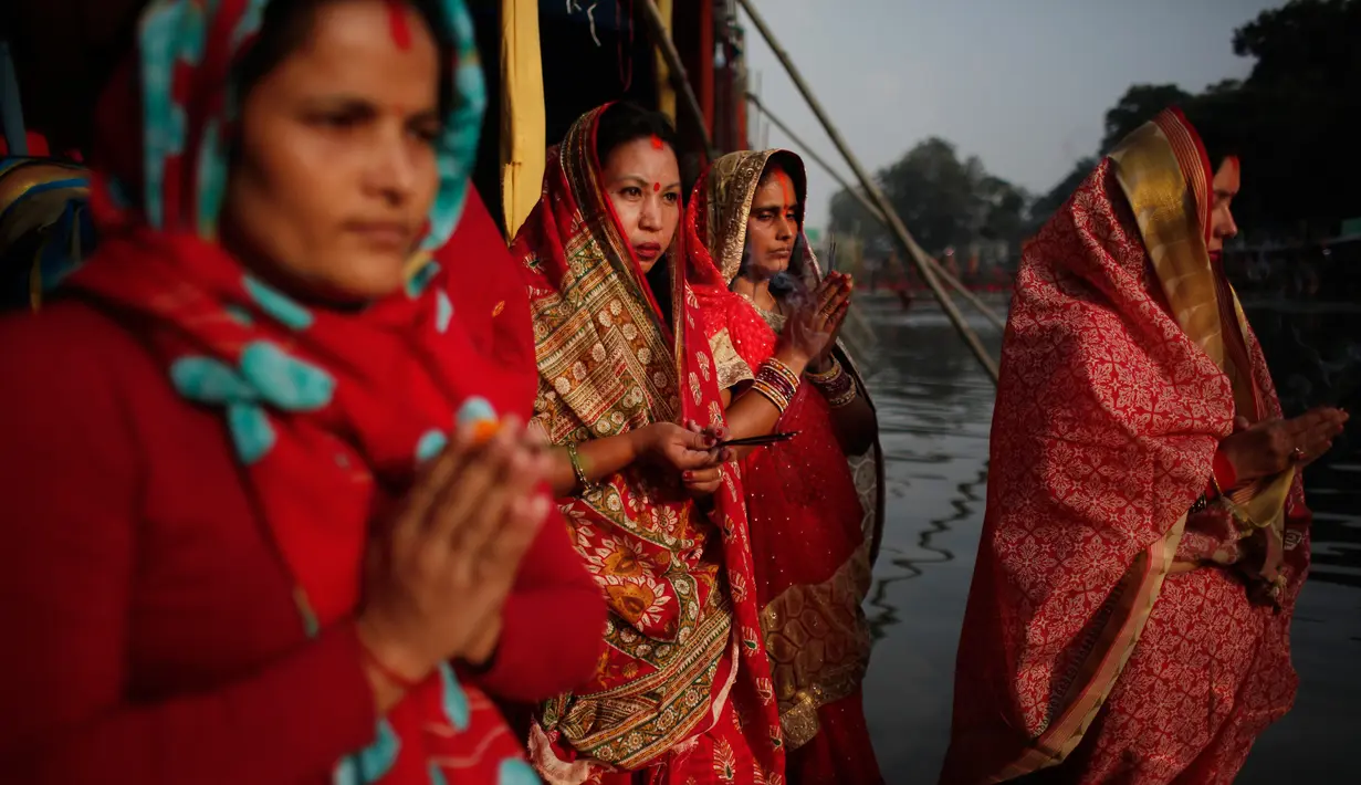 Sejumlah wanita Nepal berdoa saat matahari terbenam selama festival Chhath Puja di tepi Sungai Bagmati, Kathmandu, Nepal (26/10). Mereka berterima kasih kepada Dewa Matahari atas kehidupan yang diberikan. (AP Photo/Niranjan Shrestha)