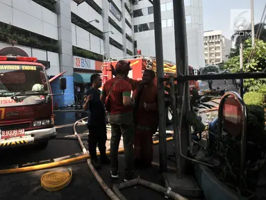 Suasana saat petugas pemadam melakukan pendinginan dan penyisiran di sekitar lokasi kebakaran Gedung Kementerian Perhubungan (Kemenhub), Jakarta, Minggu (8/7). Dalam kebakaran tersebut dilaporkan 3 orang tewas. (Merdeka.com/Iqbal S Nugroho)