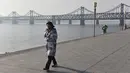 Seorang wanita di dekat Jembatan Persahabatan di kota Dandong di provinsi Liaoning, China (22/2). Jembatan Persahabatan merupakan salah satu dari beberapa cara untuk memasuki atau meninggalkan Korea Utara. (AFP Photo/Greg Baker)