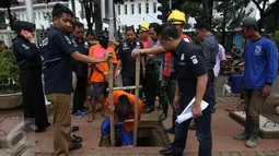 Para tersangka masuk ke dalam lubang gorong-gorong saat rekonstruksi pencurian kabel di Jalan Medan Merdeka Selatan, Jakarta, Selasa (15/3). 4 tersangka dihadirkan untuk menunjukkan cara mereka memotong dan mencuri kabel. (Liputan6.com/Immanuel Antonius)