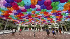 Pengunjung melewati instalasi Umbrella Sky Project di Aix-en-Provence, Prancis, Jumat (28/6/2019). Spot berteduh yang instagramable tersebut merupakan karya seniman Portugis Patricia Cunha. (BORIS HORVAT/AFP)