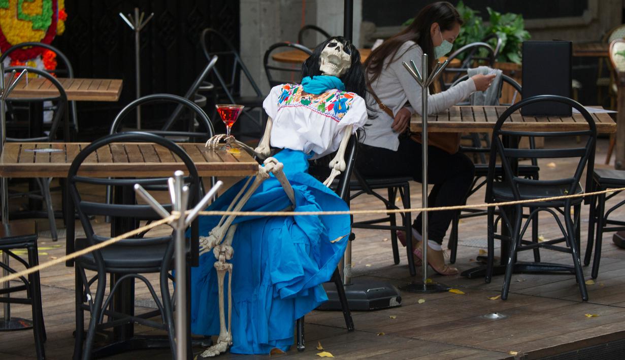 Pemandangan yang disebut Calaca (sosok tengkorak atau kerangka), yang biasa digunakan untuk dekorasi selama Day of the Death, di sebuah restoran di Coyoacan, Mexico City, Selasa (20/10/2020). Restoran tersebut menggunakan tengkorak untuk menjaga jarak di tengah pandemi COVID-19. (CLAUDIO CRUZ/AFP)