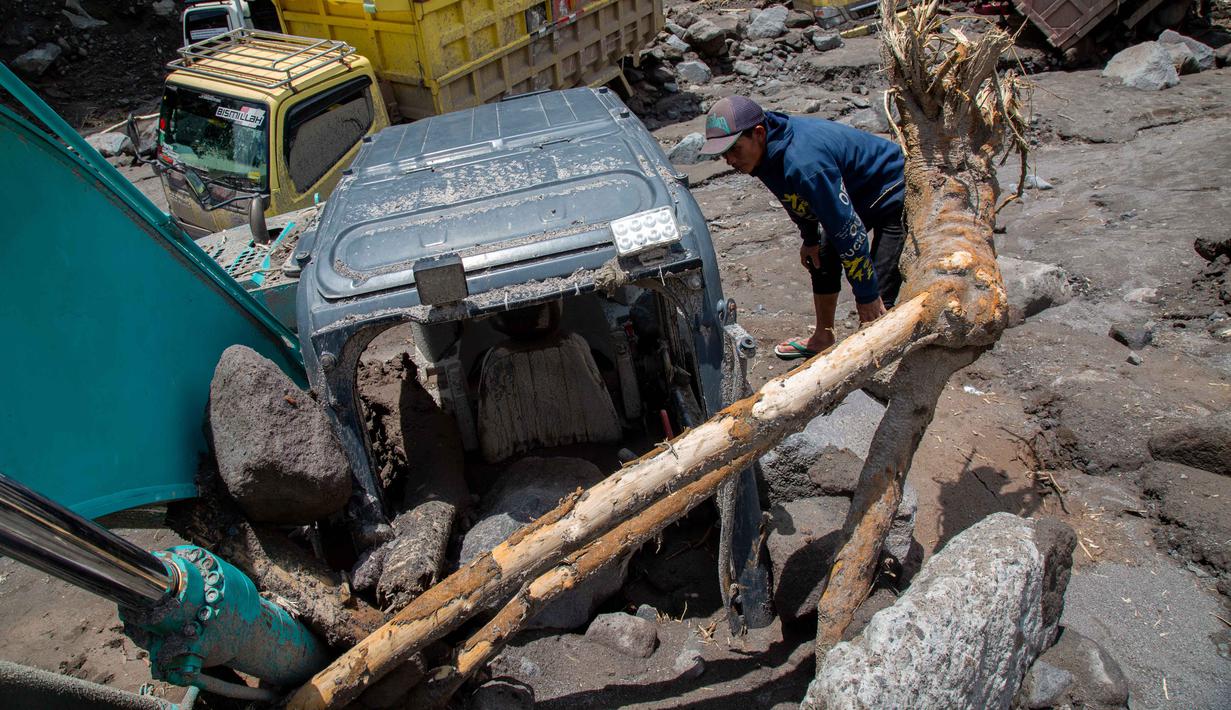 Banjir lahar dingin ini dipicu oleh hujan deras di wilayah hulu Merapi sejak siang hari, yang kemudian menghantam area penambangan pasir. Tampak dalam foto, warga berusaha mengambil bagian-bagian truk yang terkubur di pasir setelah longsor lumpur akibat hujan dari Gunung Merapi di Sungai Senowo, Magelang, Jawa Tengah pada Rabu 4 Maret 2026. (Devi Rahman/AFP)