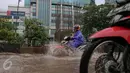 Pengendara motor melewati genangan air di kawasan Kuningan, Jakarta, Selasa (24/11). Jalur lambat di Jalan HR Rasuna Said, Kuningan, tampak dihindari pengendara karena terdapat genagan air setinggi 20 cm. (Liputan6.com/Faizal Fanani)
