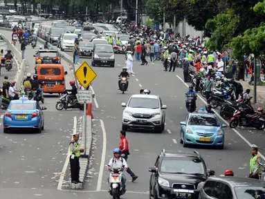 Polisi mengatur lalu lintas di Jalan Medan Merdeka Timur usai ribuan massa ormas melakukan unjuk rasa di Bareskrim Polri, Gedung KKP Jakarta, Jumat (14/10). Dalam aksinya, massa meminta Basuki Tjahaja Purnama ditahan. (Liputan6.com/Helmi Fithriansyah)