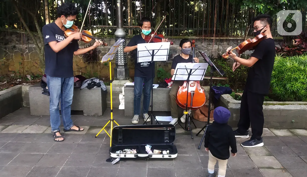 Musisi lokal Bogor memainkan musik klasik di pedestrian Kebun Raya, Jalan Pajajaran, Bogor, Jawa Barat, Minggu (14/6/2020). Untuk memenuhi kebutuhan hidup akibat sepinya job pertunjukan selama pandemi COVID-19, mereka memilih mengamen saat warga berolahraga. (merdeka.com/Arie Basuki)
