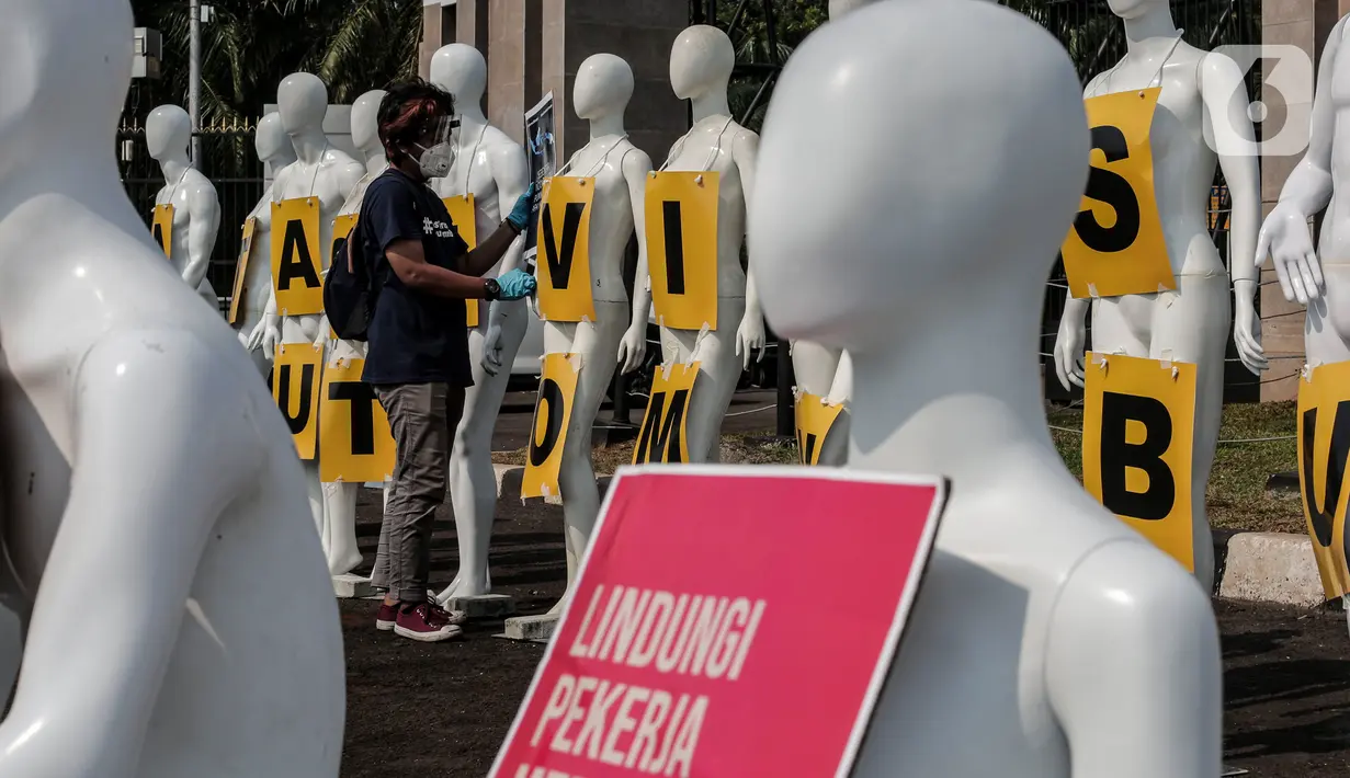 Aktivis Greenpeace Indonesia memasang poster pada puluhan maneken saat menggelar aksi damai di depan gerbang kompleks DPR, Jakarta Pusat, Senin (29/6/2020). Aksi tersebut dilakukan sebagai bentuk penolakan terhadap RUU Omnibus Law. (Liputan6.com/Johan Tallo)