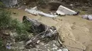 Sebuah mobil tergeletak di sungai setelah hujan lebat di Thessaloniki, Yunani utara, Sabtu, 17 Juni 2023. Rumah-rumah terendam banjir dan pohon-pohon tumbang serta mobil-mobil hanyut setelah hujan lebat di banyak pinggiran kota di bagian utara. (AP Photo/Giannis Papanikos)