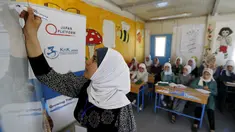 Pengungsi asal Suriah, Omayma Al Hushan saat menulis di hadapan rekan-rekannya mengenai perlawanan terhadap pernikahan di bawah umur di sebuah sekolah di kamp pengungsi Al Zaatari, Mafraq, Yordania (21/4). (REUTERS / Muhammad Hamed)