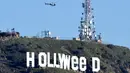Helikopter terbang di atas tanda ikonik Hollywood yang diubah menjadi Hollyweed  di Hollywood Hills, Los Angeles, Minggu (1/1). Sebelumnya, ini telah diubah menjadi Hollyweed pada tahun 1976 oleh seorang bernama Danny Finegood. (AFP PHOTO/Gene Blevins)
