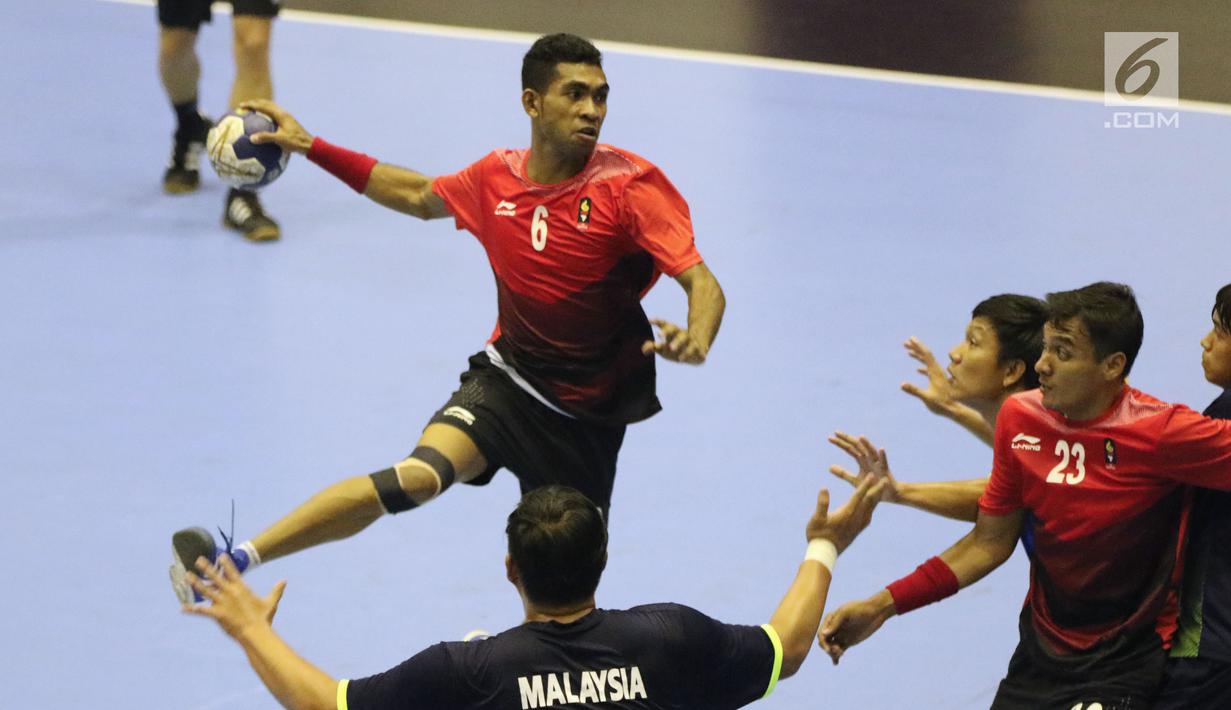 Pemain bola tangan Indonesia, Oni Arianus (kiri) mencoba membongkar pertahanan Malaysia pada penyisihan grup 3 bola tangan Asian Games 2018 di GOR PP POPKI, Jakarta, Minggu (26/8). Indonesia unggul 31-22. (Liputan6.com/Helmi Fithriansyah)