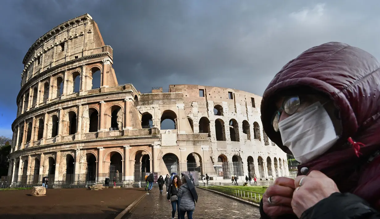 Seorang pria mengenakan masker pelindung melewati Colosseum di Roma, Italia, 7 Maret 2020. Hingga 21 Maret 2013, sebanyak 47.021 orang terinfeksi virus corona COVID-19 di Italia dengan korban meninggal mencapai 4.032 orang. (Photo by Alberto PIZZOLI/AFP)