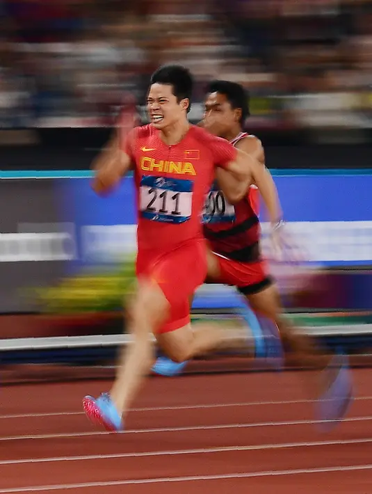 Pelari China, Su Bingtian (kiri) memacu kecepatan saat berkompetisi pada Final nomor Lari 100 meter putra Asian Games 2018 di Stadion Gelora Bung Karno, Jakarta, Minggu (26/8). Su Bingtian meraih emas dengan catatan waktu 9,92 detik. (AFP/Martin BUREAU)