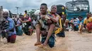 Warga menggendong seorang perempuan sementara lainnya menyeberangi banjir di distrik Ndjili, Kinshasa, pada 6 April 2025. (Hardy BOPE/AFP)