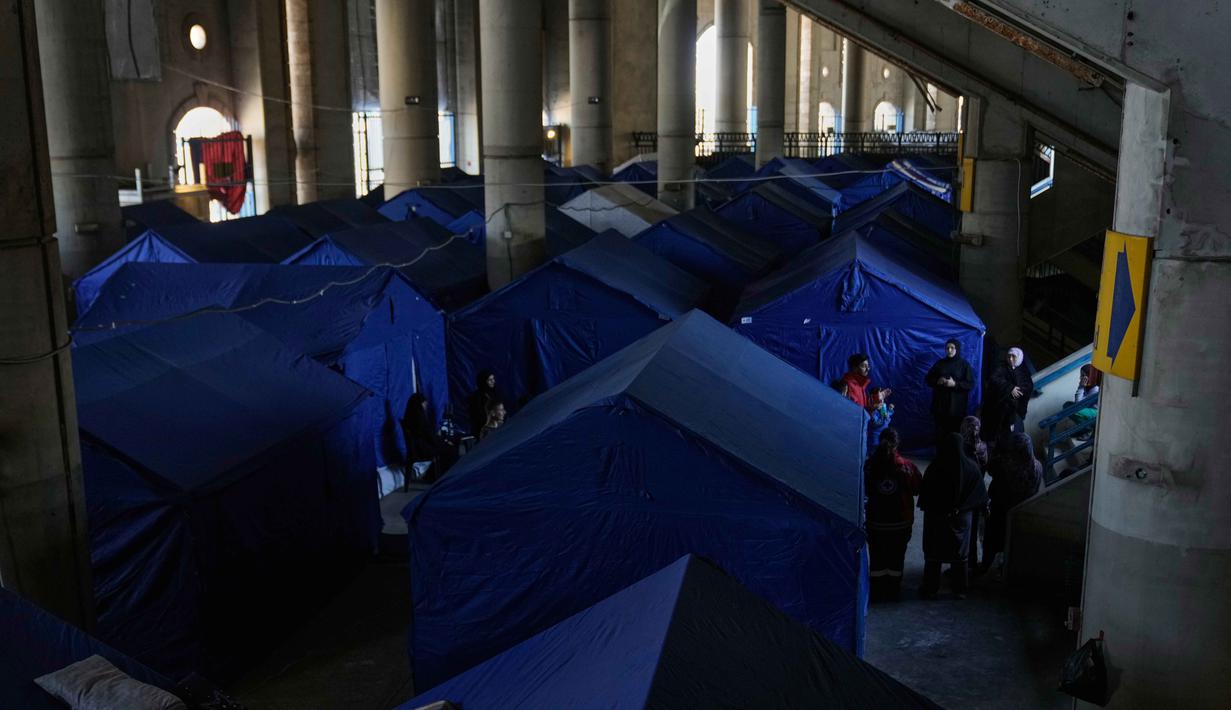 Langkah darurat ini diambil menyusul eskalasi konflik antara Israel dan Hizbullah yang pecah kembali sejak Maret 2026. Tampak dalam foto, para pengungsi berdiri di samping tenda-tenda yang didirikan di dalam Camille Chamoun Sports City Stadium, yang telah diubah menjadi tempat penampungan bagi orang-orang yang melarikan diri dari serangan udara Israel di Lebanon selatan, Beirut, Lebanon, Rabu 8 April 2026. (AP Photo/Bilal Hussein)