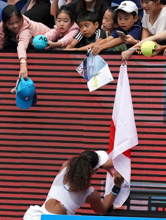 Petenis Jepang Naomi Osaka menandatangani bendera yang disodorkan penonton usai mengalahkan petenis Republik Ceko Marie Bouzkova pada Australia Terbuka di Melbourne, Australia, Senin (20/1/2020). Penonton menyodorkan topi, bendera, hingga bola untuk ditandatangani Naomi. (AP Photo/Lee Jin-man)