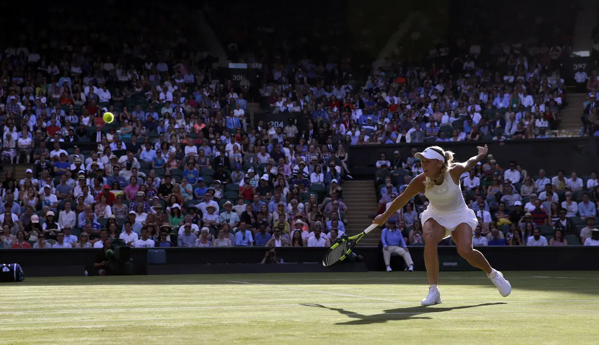 Aksi Caroline Wozniacki saat mengembalikan bola ke arah Timea Babos pada laga tunggal putri Wimbledon 2017 di Wimbledon Tennis Championships, London, (4/7/2017). Wozniacki menang 6-4, 4-6, 6-1. (AP/Alastair Grant)