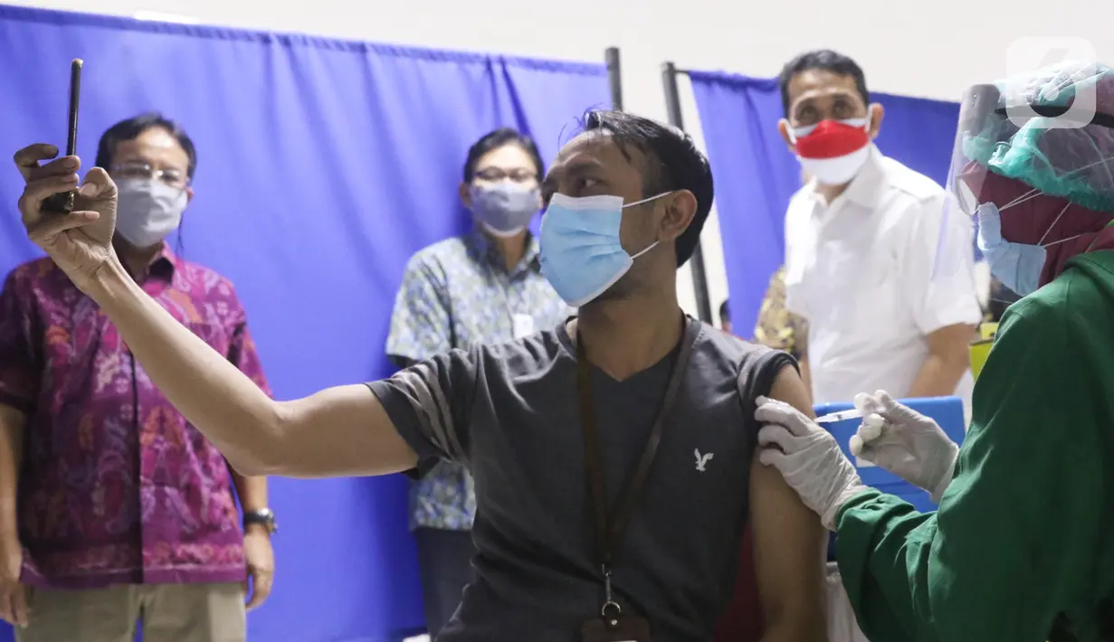 Warga mengabadikan momen saat vaksinasi covid-19 di sentra vaksin Tomang Tol Plaza, Tangerang, Sabtu (24/7/2021). Pemerintah sebelumnya menetapkan target sasaran vaksinasi 181,5 juta atau 70 persen dari total populasi untuk mencapai kekebalan kelompok atau herd immunity. (Liputan6.com/Angga Yuniar)