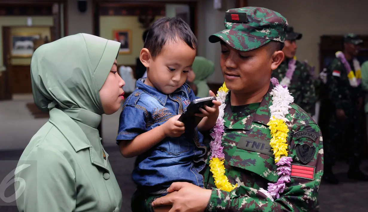 Seorang anak memainkan telepon genggam sang ayah usai penyambutan kedatangan kontingen AASAM di Bandara Soetta, Banten, Senin (23/5/2016). TNI AD menjadi juara umum AASAM 2016 yang digelar di Australia. (Liputan6.com/Helmi Fithriansyah